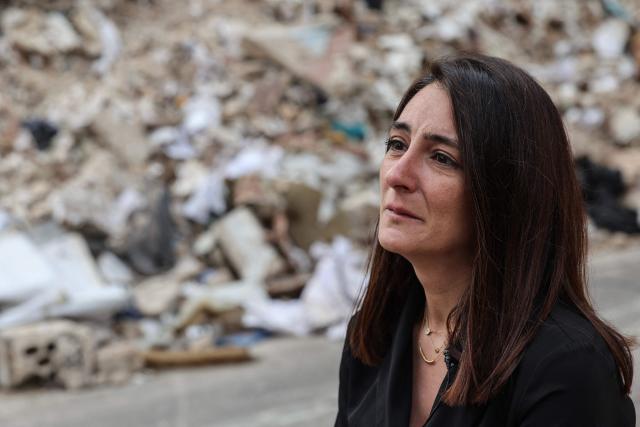 Ghida Krisht, who lost her mother and father when their house in Beirut’s Tallet el-Khayat, an affluent residential neighborhood was struck by an Israeli strike in April, stands in front of the remains of the building on May 18, 2026. Standing in front of their parents’ building, which was destroyed by an Israeli strike in Beirut, Ghida Krisht and Wael Sabbagh make a solemn vow: to seek justice through international bodies for their slain families. On this April 8, the “Black Wednesday” when massive Israeli strikes killed more than 350 people in Lebanon according to authorities, Ghida lost her parents and a close relative, and Wael lost his mother and brother. The final strike on Beirut that day targeted the building where they had lived for some fifty years in Tallet el-Khayat, an affluent residential neighborhood where they believed they were safe. (Photo by Anwar AMRO / AFP)