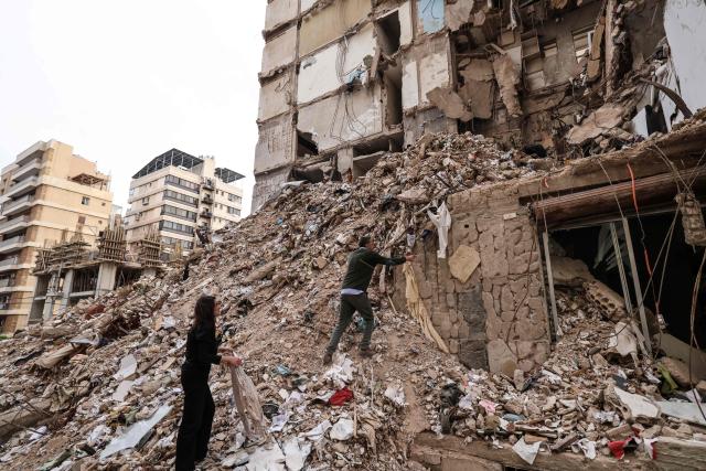 Ghida Krisht (L) and Wael Sabbagh, who both lost relatives when their apartments in Beirut’s Tallet el-Khayat, an affluent residential neighborhood were struck by an Israeli strike in April, inspect the rubble of the building on May 18, 2026.”. Standing in front of their parents’ building, which was destroyed by an Israeli strike in Beirut, Ghida Krisht and Wael Sabbagh make a solemn vow: to seek justice through international bodies for their slain families. On this April 8, the “Black Wednesday” when massive Israeli strikes killed more than 350 people in Lebanon according to authorities, Ghida lost her parents and a close relative, and Wael lost his mother and brother. The final strike on Beirut that day targeted the building where they had lived for some fifty years in Tallet el-Khayat, an affluent residential neighborhood where they believed they were safe. (Photo by Anwar AMRO / AFP)