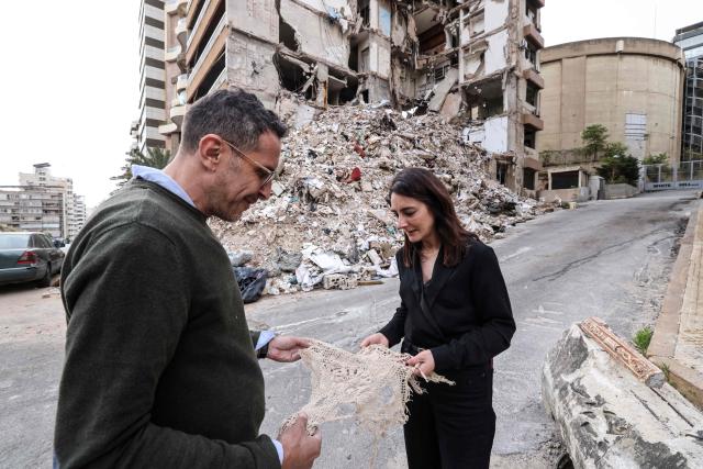 Wael Sabbagh (L) and Ghida Krisht, who both lost relatives when their apartments in Beirut’s Tallet el-Khayat, an affluent residential neighborhood were struck by an Israeli strike in April, look at a piece of fabric recovered from the rubble of the building on May 18, 2026.”. Standing in front of their parents’ building, which was destroyed by an Israeli strike in Beirut, Ghida Krisht and Wael Sabbagh make a solemn vow: to seek justice through international bodies for their slain families. On this April 8, the “Black Wednesday” when massive Israeli strikes killed more than 350 people in Lebanon according to authorities, Ghida lost her parents and a close relative, and Wael lost his mother and brother. The final strike on Beirut that day targeted the building where they had lived for some fifty years in Tallet el-Khayat, an affluent residential neighborhood where they believed they were safe. (Photo by Anwar AMRO / AFP)