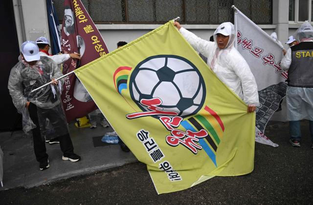 A South Korean supporter for North Korea's Naegohyang Women's FC holds a flag of the Naegohyang team as he prepares to enter the stadium before the AFC Women's Champions League semi-final football match between North Korea's Naegohyang Women's FC and South Korea's Suwon FC Women in Suwon on May 20, 2026. (Photo by Jung Yeon-je / AFP)