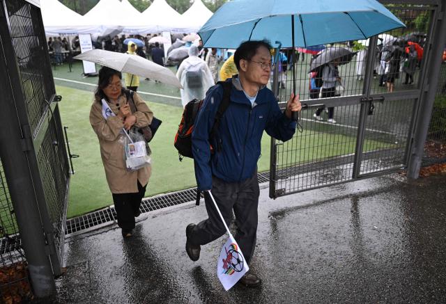South Korean supporters for North Korea's Naegohyang Women's FC carry flags of the Naegohyang team at a ticket booth for the AFC Women's Champions League semi-final football match between North Korea's Naegohyang Women's FC and South Korea's Suwon FC Women in Suwon on May 20, 2026. (Photo by Jung Yeon-je / AFP)