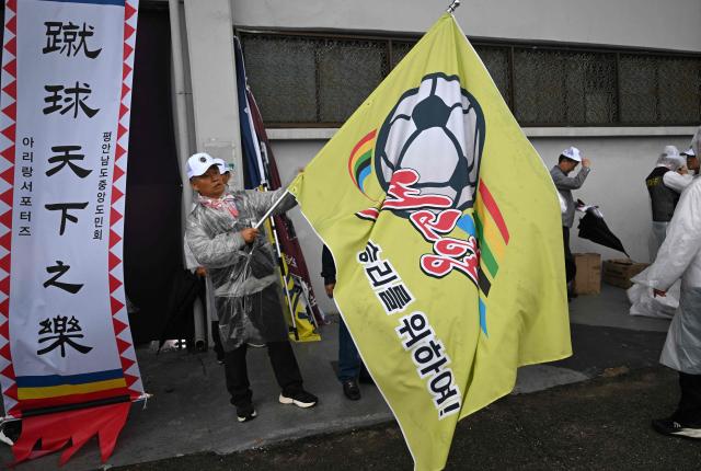 A South Korean supporter for North Korea's Naegohyang Women's FC holds a flag of the Naegohyang team as he prepares to enter the stadium before the AFC Women's Champions League semi-final football match between North Korea's Naegohyang Women's FC and South Korea's Suwon FC Women in Suwon on May 20, 2026. (Photo by Jung Yeon-je / AFP)