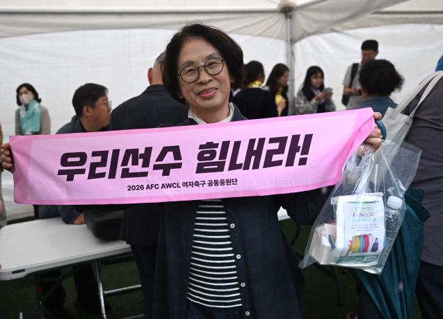 A South Korean supporter for North Korea's Naegohyang Women's FC holds a banner reading "Cheer up, our player!" at a ticket booth for the AFC Women's Champions League semi-final football match between North Korea's Naegohyang Women's FC and South Korea's Suwon FC Women in Suwon on May 20, 2026. (Photo by Jung Yeon-je / AFP)