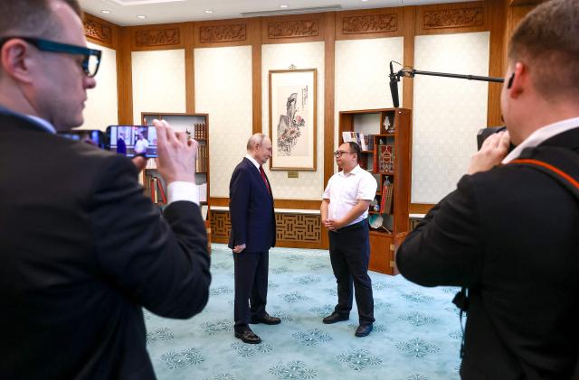 In this pool photograph distributed by the Russian state agency Sputnik, Russia's President Vladimir Putin meets with Chinese engineer Peng Pai 26 years since their encounter during the Russian leader's visit to China, in Beijing on May 20, 2026. (Photo by Vladimir SMIRNOV / POOL / AFP)