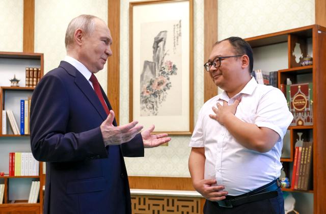 In this pool photograph distributed by the Russian state agency Sputnik, Russia's President Vladimir Putin meets with Chinese engineer Peng Pai 26 years since their encounter during the Russian leader's visit to China, in Beijing on May 20, 2026. (Photo by Vladimir SMIRNOV / POOL / AFP)