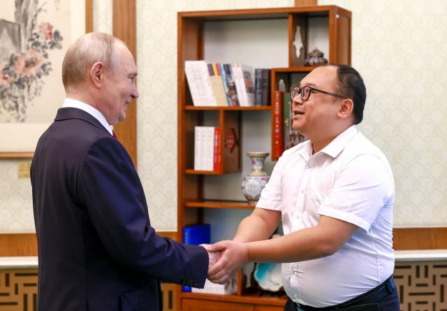 In this pool photograph distributed by the Russian state agency Sputnik, Russia's President Vladimir Putin meets with Chinese engineer Peng Pai 26 years since their encounter during the Russian leader's visit to China, in Beijing on May 20, 2026. (Photo by Vladimir SMIRNOV / POOL / AFP)