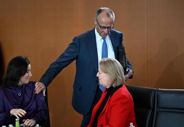 German Chancellor Friedrich Merz (C) walks past German Minister for Research, Technology and Aerospace Dorothee Baer (L) and German Minister for Labour and Social Affairs Baerbel Bas (R) as he arrives to lead the weekly cabinet meeting at the Chancellery in Berlin on May 20, 2026. (Photo by Tobias SCHWARZ / AFP)