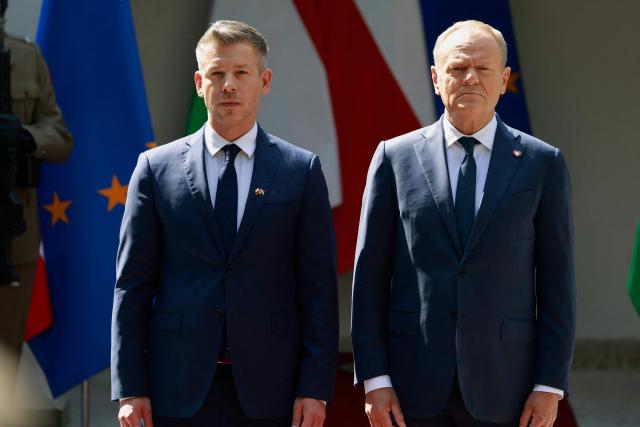 Poland's Prime Minister Donald Tusk (R) and Hungary's Prime Minister Peter Magyar (L) stand as they review a military honor guard in Warsaw, Poland, on May 20, 2026. Hungary's new Prime Minister Peter Magyar is on a two-day visit to Poland for his first official trip abroad, hoping to mark his country's re-alignment with the European Union after years of open conflict under his predecessor. (Photo by Wojtek RADWANSKI / AFP)