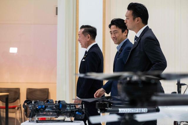 Japan's Defense Minister Shinjiro Koizumi (C) walks onto the factory floor with Shunsuke Toya (L), CEO and President of Prodrone, at the Prodrone research facility in Nagoya on May 20, 2026, as Japan pushes to expand military drone capabilities with nearly USD 850 million earmarked for unmanned defense systems in its 2026 defense budget. (Photo by ANDREW CABALLERO-REYNOLDS / AFP)