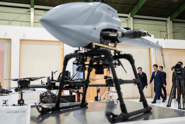Japan's Defense Minister Shinjiro Koizumi (C) walks onto the factory floor with Shunsuke Toya (L), CEO and President of Prodrone, at the Prodrone research facility in Nagoya on May 20, 2026, as Japan pushes to expand military drone capabilities with nearly USD 850 million earmarked for unmanned defense systems in its 2026 defense budget. (Photo by ANDREW CABALLERO-REYNOLDS / AFP)