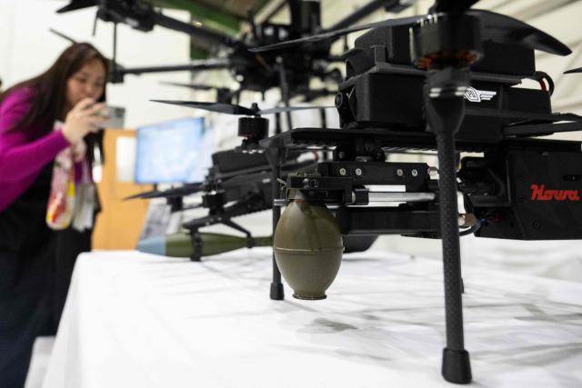 A journalist takes photos of armed drone models at the Prodrone research facility in Nagoya on May 20, 2026, as Japan pushes to expand military drone capabilities with nearly USD 850 million earmarked for unmanned defense systems in its 2026 defense budget. (Photo by ANDREW CABALLERO-REYNOLDS / AFP)