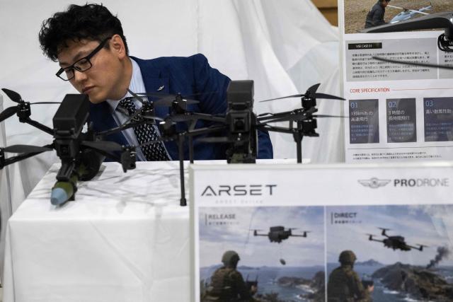 An employee looks at armed drone models at the Prodrone research facility in Nagoya on May 20, 2026, as Japan pushes to expand military drone capabilities with nearly USD 850 million earmarked for unmanned defense systems in its 2026 defense budget. (Photo by ANDREW CABALLERO-REYNOLDS / AFP)