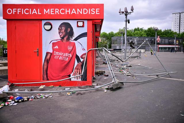 Broken fences are pictured in front of a Merchandise stall outside the Emirates Stadium in London on May 20, 2026, the day after Arsenal won the English Premier League. Arsenal celebrated their first Premier League title for 22 years on Tuesday after Manchester City were held to a 1-1 draw by Bournemouth, sparking wild scenes of joy around the Emirates Stadium. (Photo by Ben STANSALL / AFP)