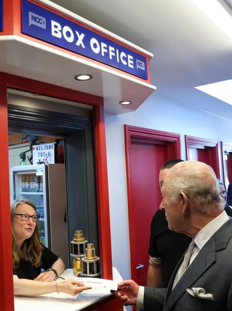 Britain's King Charles III shakes hands as he receives a cinema ticket from Vera Edelstein at the box office, during a visit to Newcastle Community Cinema, in Newcastle, south of Belfast, Northern Ireland on May 20, 2026, on the second day of a three-day royal visit to Northern Ireland. (Photo by Toby Melville / POOL / AFP)