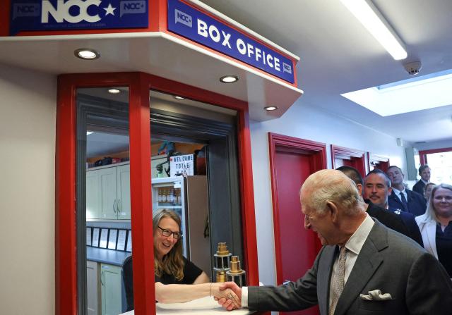 Britain's King Charles III shakes hands as he receives a cinema ticket from Vera Edelstein at the box office, during a visit to Newcastle Community Cinema, in Newcastle, south of Belfast, Northern Ireland on May 20, 2026, on the second day of a three-day royal visit to Northern Ireland. (Photo by Toby Melville / POOL / AFP)