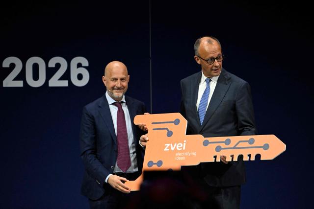 German Chancellor Friedrich Merz (R) is handed over a symbolic key by President of ZVEI Association Daniel Hager during the opening of the so-called eSummit organised by the ZVEI Association of the German electro and digital industry, in Berlin on May 20, 2026. (Photo by Tobias SCHWARZ / AFP)