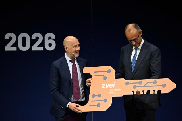German Chancellor Friedrich Merz (R) is handed over a symbolic key by ZVEI President Daniel Hager during the opening of the so-called eSummit organised by the ZVEI Association of the German electro and digital industry, in Berlin on May 20, 2026. (Photo by Tobias SCHWARZ / AFP)