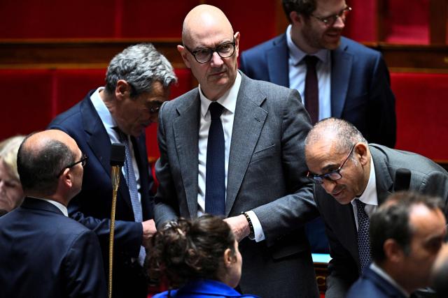 France's Economy, Finances and Industry Minister Roland Lescure (C) reacts upon arrival to attend a session of questions to the government at The National Assembly, France's lower house of parliament in Paris on May 20, 2026. (Photo by JULIEN DE ROSA / AFP)