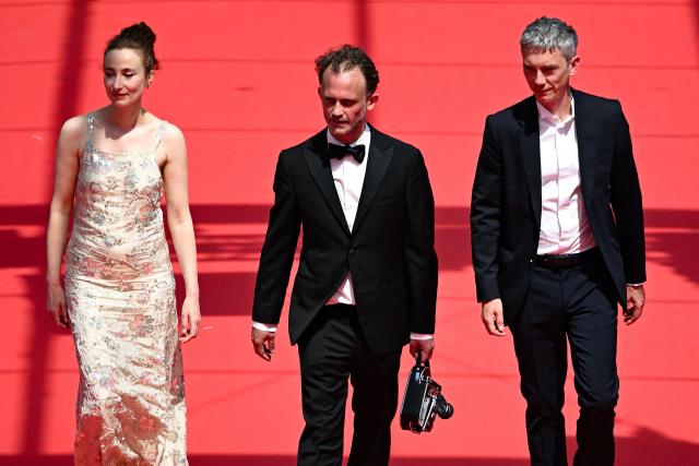 (FROM L) Belgian actress Sandrine Blancke, French director and screenwriter Emmanuel Marre and French actor Swann Arlaud arrive for the screening of the film "Notre Salut" (A Man of His Time) at the 79th edition of the Cannes Film Festival in Cannes, southern France on May 20, 2026. (Photo by Antonin THUILLIER / AFP)