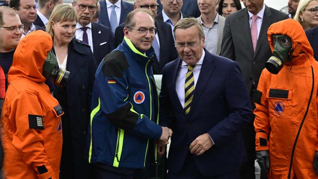 Germany's Interior Minister Alexander Dobrindt (C-L) and Germany's Defence Minister Boris Pistorius (C-R) shake hands as first responders stand during a hand over of special vehicles for the civil protection to volunteer emergency personnel in Berlin, on May 20, 2026. On May 20, 2026, six CBRN (Chemical, Biological, Radiological and Nuclear Hazards) command personnel carriers for casualty decontamination (MTW Fü Dekon V) and six federal civil protection ambulances (KTW Typ B) from the Federal Office of Civil Protection and Disaster Assistance (BBK) are handed over to emergency services of the States of Berlin, Brandenburg and Thuringia, as well as a THW personnel carrier to Baden-Württemberg. (Photo by John MACDOUGALL / AFP)
