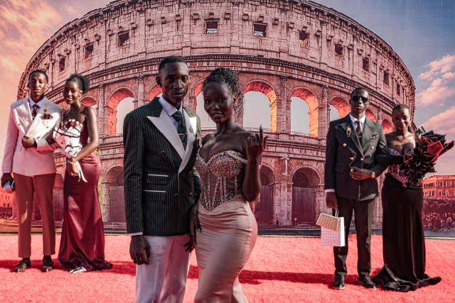 TOPSHOT - Senior year students at St. Julian High School pose for pictures during their arrival at their prom party themed “A Night in Italy” in Gayaza, on May 19, 2026. Uganda’s high school proms, influenced by global youth and celebrity culture and amplified by social media, have become lavish celebrations blending fashion, creativity and status with local styles of celebration. Mostly seen in elite and urban schools, the events feature themed decor, luxury arrivals and elaborate outfits, with some students previously making headlines for arriving by helicopter before the government banned helicopters and luxury SUV's at school events. Schools balance student expression and modern trends with cultural values and stricter government regulations. (Photo by Badru Katumba / AFP)