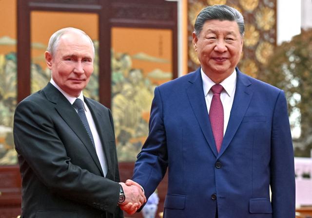 In this pool photograph distributed by the Russian state agency Sputnik, Russia's President Vladimir Putin and China's President Xi Jinping hold a tea chat in Beijing on May 20, 2026. (Photo by Kristina Solovyova / POOL / AFP)