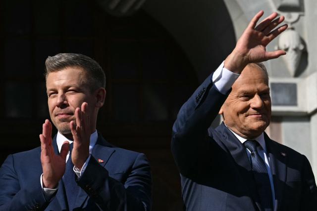 Poland's Prime Minister Donald Tusk (R) and Hungary's Prime Minister Peter Magyar (L) wave to supporters after a meeting with former leader of Solidarnosc and former President of Poland Lech Walesa (unseen) in Gdansk, Poland, on May 20, 2026. Hungary's new Prime Minister Peter Magyar is on a two-day visit to Poland for his first official trip abroad, hoping to mark his country's re-alignment with the European Union after years of open conflict under his predecessor. (Photo by Sergei GAPON / AFP)