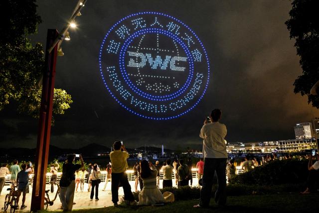 People enjoy a drone show at the Sea World Culture and Arts Center (SWCAC) in Shenzhen, southern China's Guangdong province on May 20, 2026, on the eve of Drone World Congress (DWC). (Photo by Hector RETAMAL / AFP)