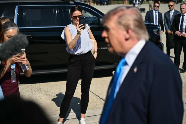 Margo Martin, Special Assistant to the President and Communications Advisor, takes video on her phone as US President Donald Trump speaks to reporters before boarding Air Force One at Joint Base Andrews, Maryland on May 20, 2026. Trump is heading to New London, Connecticut, to deliver the commencement address to the US Coast Guard Academy's 2026 graduating class. (Photo by Kent NISHIMURA / AFP)