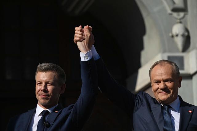 Poland's Prime Minister Donald Tusk and Hungary's Prime Minister Peter Magyar hold hands during a rally in Gdansk on May 20, 2026. Hungary's new Prime Minister Peter Magyar is on a two-day visit to Poland for his first official trip abroad, hoping to mark his country's re-alignment with the European Union after years of open conflict under his predecessor. (Photo by Sergei GAPON / AFP)