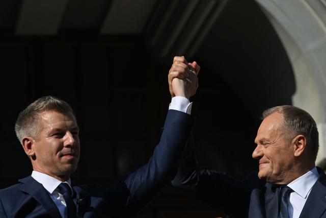 Poland's Prime Minister Donald Tusk and Hungary's Prime Minister Peter Magyar hold hands during a rally in Gdansk on May 20, 2026. Hungary's new Prime Minister Peter Magyar is on a two-day visit to Poland for his first official trip abroad, hoping to mark his country's re-alignment with the European Union after years of open conflict under his predecessor. (Photo by Sergei GAPON / AFP)