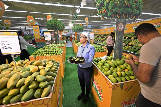 A man (R) shops for mangoes at a hypermarket during the Mango Mania Festival in Kuwait City on May 20, 2026. (Photo by YASSER AL-ZAYYAT / AFP)