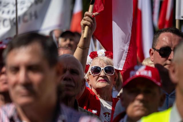 A woman holds Poland's flag during a demonstration of the "Solidarnosc" (Solidarity) trade union and right-wing supporters against the European Green Deal and the policies of Donald Tusk’s government in front the Polish parliament, the Sejm, in Warsaw, Poland, on May 20, 2026. (Photo by Wojtek RADWANSKI / AFP)