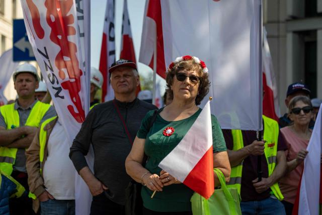 A woman holds a flag with Poland's colors during a demonstration of the "Solidarnosc" (Solidarity) trade union and right-wing supporters against the European Green Deal and the policies of Donald Tusk’s government in front the Polish parliament, the Sejm, in Warsaw, Poland, on May 20, 2026. (Photo by Wojtek RADWANSKI / AFP)