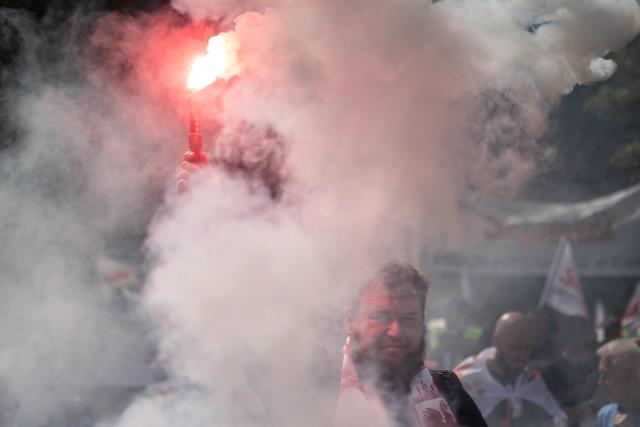 A protester holds a burning flare during during a demonstration of the "Solidarnosc" (Solidarity) trade union and right-wing supporters against the European Green Deal and the policies of Donald Tusk’s government in front the Polish parliament, the Sejm, in Warsaw, Poland, on May 20, 2026. (Photo by Wojtek RADWANSKI / AFP)