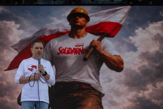 Piotr Duda - leader of the "Solidarnosc" (Solidarity) trade union, speaks in front the image of a man with helmet and a flag during a demonstration of right-wing supporters against the European Green Deal and the policies of Donald Tusk’s government in front the Polish parliament, the Sejm, in Warsaw, Poland, on May 20, 2026. (Photo by Wojtek RADWANSKI / AFP)