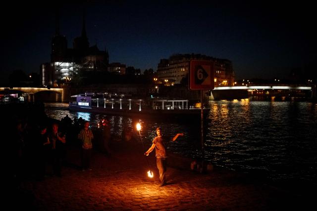 (From L) Guest, Guest, Guest and Guest A fire spinner performs on the banks of the Seine River in Paris on May 20, 2026.   Photo by Dimitar DILKOFF / AFP) (Photo by DIMITAR DILKOFF / AFP)