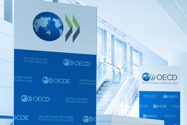 This photograph taken on September 22, 2025 shows the logo of the Organisation for Economic Cooperation and Development (OECD) displayed on banners at the OECD headquarters in Paris. Wealthy countries topped their $100 billion annual climate finance goal for poorer countries in 2023 and 2024, the OECD said on May 21, 2026, marking three straight years of meeting the target. After providing $115.9 billion in 2022, wealthy countries sharply raised their contribution to $132.8 billion in 2023 and delivered $136.7 billion in 2024, according to the Organisation for Economic Cooperation and Development, which tracks the figures. (Photo by JOEL SAGET / AFP)