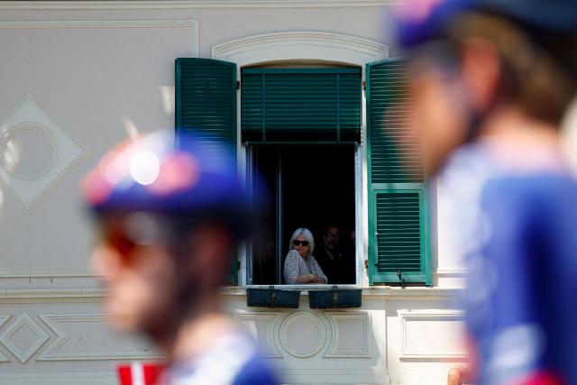 Local residents look out of an appartment window as riders prepare to compete in the 12th stage of the Giro d'Italia 2026 - Tour of Italy cycling race between Imperia and Novi Ligure, Italy, on May 21, 2026. (Photo by Luca Bettini / AFP)