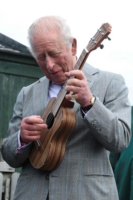 Britain's King Charles III reacts as he plays a ukulele during a visit to Ards Allotments in Newtownards, Northern Ireland on May 21, 2026, on the final day of a three-day royal visit to Northern Ireland. (Photo by Toby Melville / POOL / AFP)