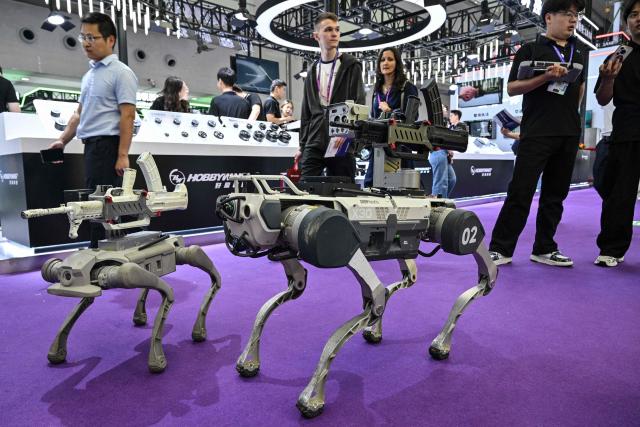 Weaponized remote-controlled robot dogs are seen during the Drone World Congress (DWC) in Shenzhen on May 21, 2026. (Photo by Hector RETAMAL / AFP)