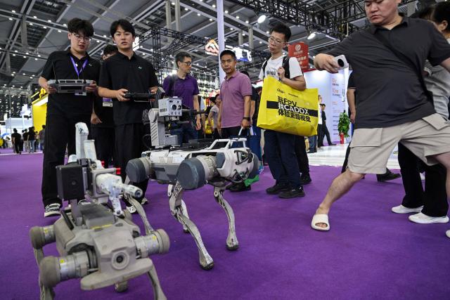 Weaponized remote-controlled robot dogs are seen during the Drone World Congress (DWC) in Shenzhen on May 21, 2026. (Photo by Hector RETAMAL / AFP)