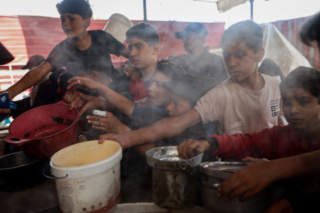 Displaced Palestinians receive food from a charity kitchen at the Nuseirat refugee camp in the central Gaza Strip on May 21, 2026. Since the terms of a US-brokered ceasefire deal came into effect on October 10, Israel remains in control of nearly half of the Gaza Strip, including all its border areas. Nearly two million people in Gaza are living in makeshift shelters, and the humanitarian situation remains dire, according to aid agencies. (Photo by Eyad BABA / AFP)