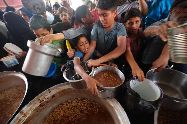Displaced Palestinians receive food from a charity kitchen at the Nuseirat refugee camp in the central Gaza Strip on May 21, 2026. Since the terms of a US-brokered ceasefire deal came into effect on October 10, Israel remains in control of nearly half of the Gaza Strip, including all its border areas. Nearly two million people in Gaza are living in makeshift shelters, and the humanitarian situation remains dire, according to aid agencies. (Photo by Eyad BABA / AFP)