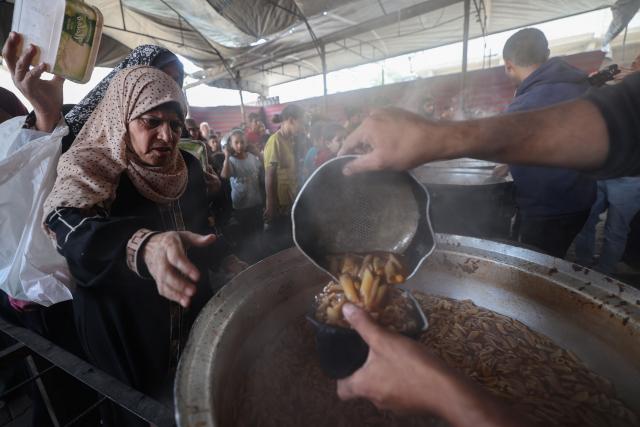 Displaced Palestinians receive food from a charity kitchen at the Nuseirat refugee camp in the central Gaza Strip on May 21, 2026. Since the terms of a US-brokered ceasefire deal came into effect on October 10, Israel remains in control of nearly half of the Gaza Strip, including all its border areas. Nearly two million people in Gaza are living in makeshift shelters, and the humanitarian situation remains dire, according to aid agencies. (Photo by Eyad BABA / AFP)