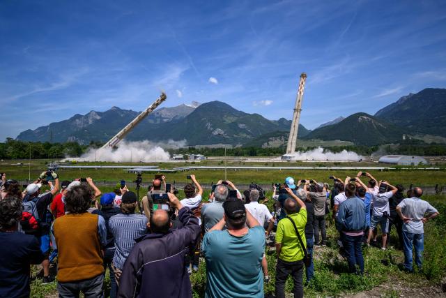Attendees watch the controlled demolition by explosion of the two 100-metre-high chimneys of a former refinery in Collombey-Muraz, south-western Switzerland on May 21, 2026. Constructed by Eni, the Collombey refinery operated from 1963 to late March 2015, closing after more than 50 years under Tamoil ownership. (Photo by Fabrice COFFRINI / AFP)