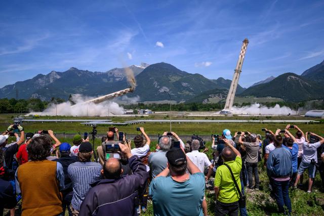 TOPSHOT - Attendees watch the controlled demolition by explosion of the two 100-metre-high chimneys of a former refinery in Collombey-Muraz, south-western Switzerland on May 21, 2026. Constructed by Eni, the Collombey refinery operated from 1963 to late March 2015, closing after more than 50 years under Tamoil ownership. (Photo by Fabrice COFFRINI / AFP)