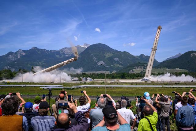People watch the controlled demolition by explosion of the two 100-meter-high chimneys of the former refinery in Collombey-Muraz on May 21, 2026. Constructed by Eni, the Collombey refinery operated from 1963 to late March 2015 was closed after more than 50 years under Tamoil ownership. (Photo by Fabrice COFFRINI / AFP)