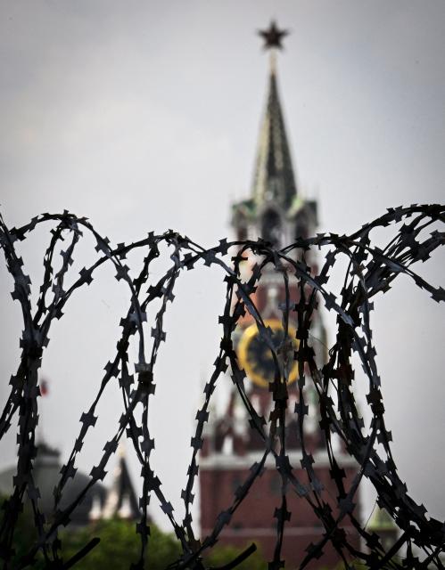 This photograph shows a view of the Spasskaya tower of the Kremlin taken on May 21, 2026 through the barbed wire of a municipal technical facility in Moscow. (Photo by Alexander NEMENOV / AFP)