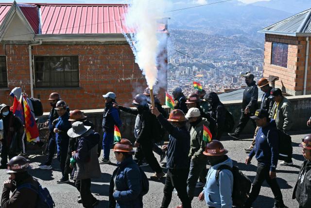 A miner holds a flare during a march organized by the Bolivian Workers' Center (COB) from El Alto to La Paz, calling for the resignation of President Rodrigo Paz, on May 21, 2026. Bolivia's centre-right President Rodrigo Paz announced on May 20 that he will make changes to his cabinet to include social sectors, in an attempt to quell protests demanding his resignation just six months after taking office. (Photo by AIZAR RALDES / AFP)